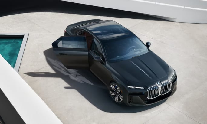 An overhead view of a black 2025 BMW 7 Series vehicle on gray pavement.