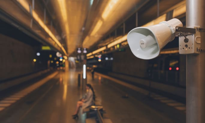 A mounted speaker above a subway platform.