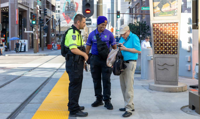 Transit security speak with a person on a sidewalk.