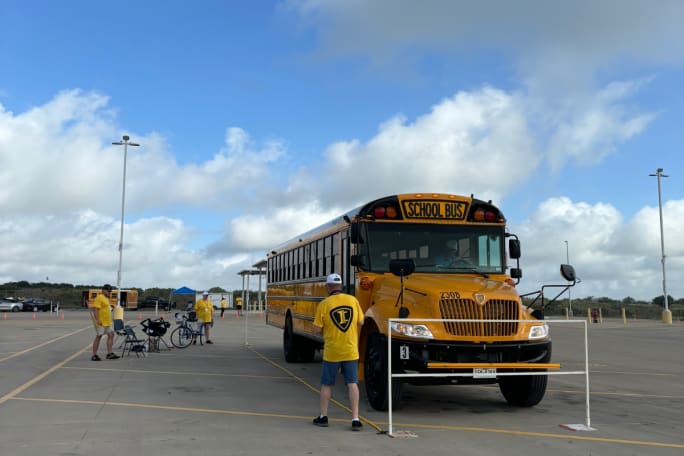 A yellow school bus is parked in a yellow boxed area with a white marker, as part of the parallel parking event.