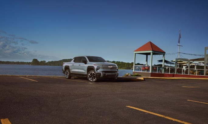A powder blue 2025 Chevrolet Silverado EV in a parking lot by the water.