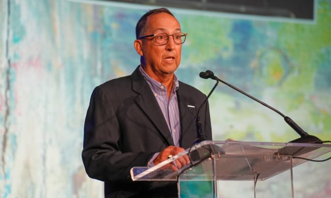 Rob Minton stands behind a podium on stage at the AFLA conference.