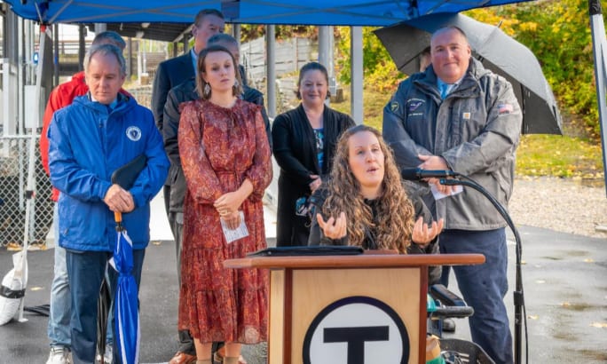Ali Rheaume speaks at a podium during the ribbon-cutting event at Franklin Station.