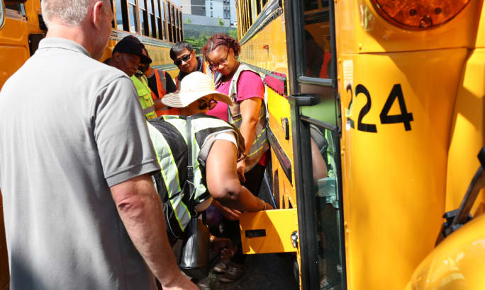 A crowd learns about the charging port on Durham School Services Ann Arbor school buses.