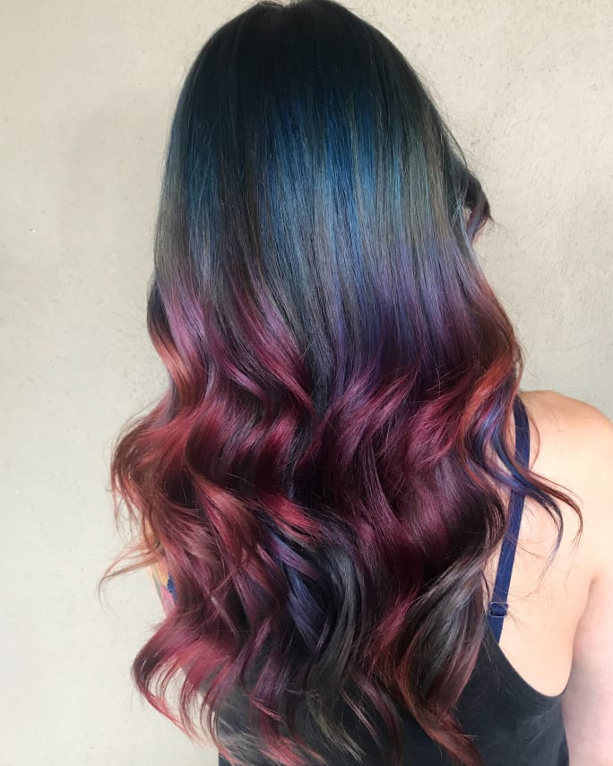 A brunette woman with pieces of bright color throughout her hair.