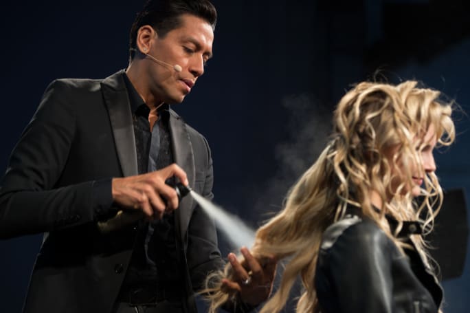 A man spraying hairspray on a model