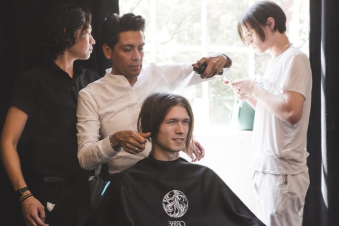 A man styling a male model's hair.