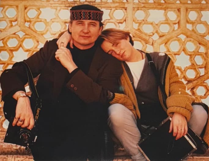A young girl leans on her father as they hold hands.
