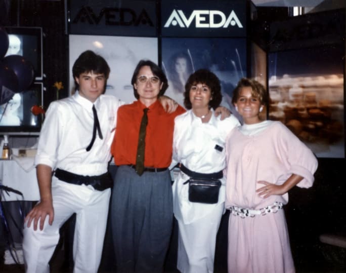 A family at a hair show with the Aveda booth behind them in the 1980s.