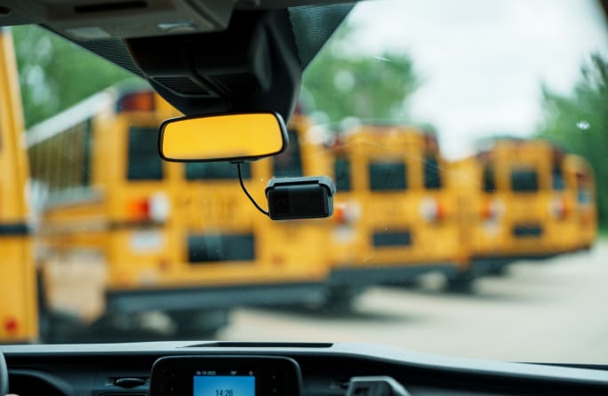 view from inside a vehicle equipped with a driver camera with school buses outside