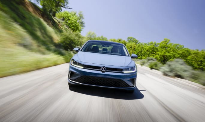 Front view of a powder blue 2025 Volkswagen Jetta driving down a road during the day.