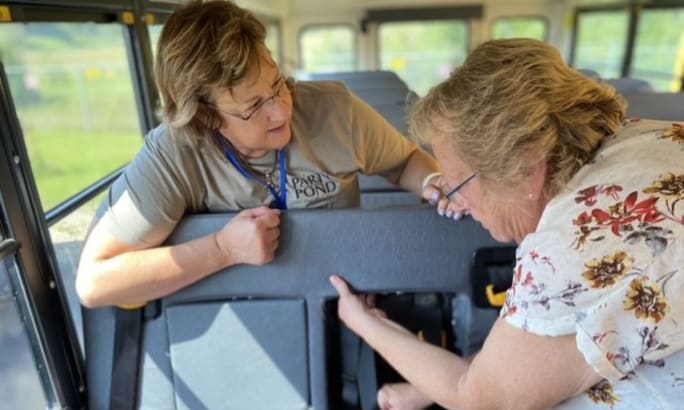 Kala Henkensiefken trains Safety Manager Monica Gregerson inside a bus.