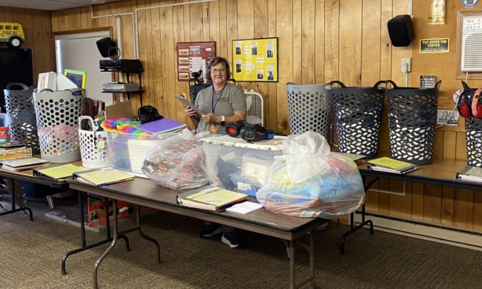 Kala Henkensiefken poses behind a table full of items and bins.