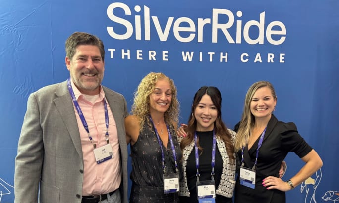 A group of SilverRide employees pose under the logo and new tag line.