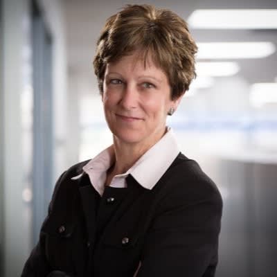 A business portrait of a woman with short brown hair and a collared shirt.