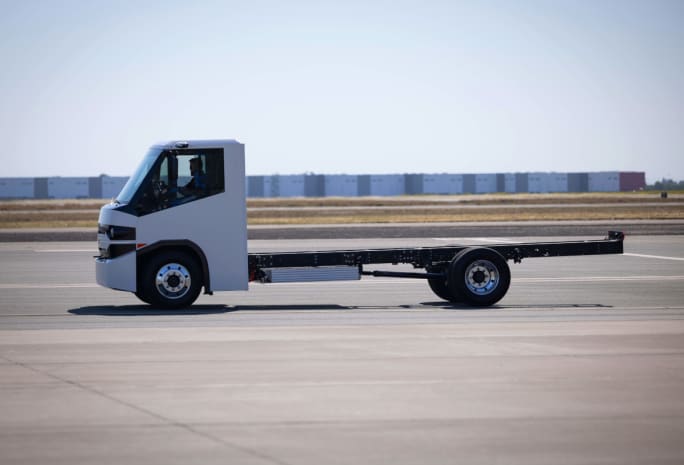 White chassis cab truck driving past, viewed from the side.