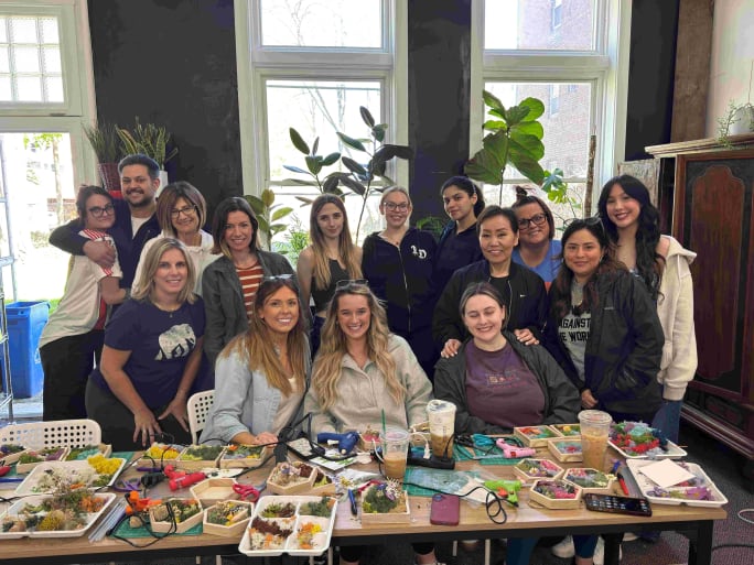 Seated behind a table full of craft materials, the team from Studio 6A Salon & Spa