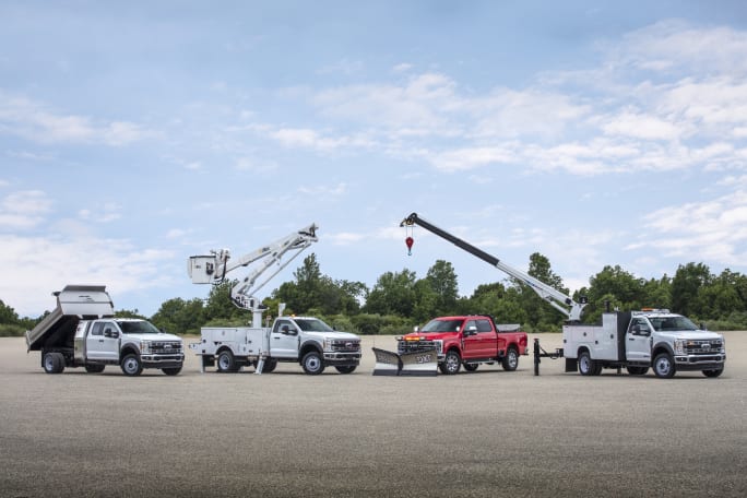 A family of upfitted Ford Super Duty trucks in a field.