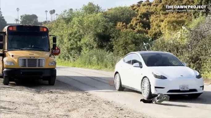 image of a tesla in self-driving mode running over a mannequin as a stopped school bus is parked nearby with its stop sign out