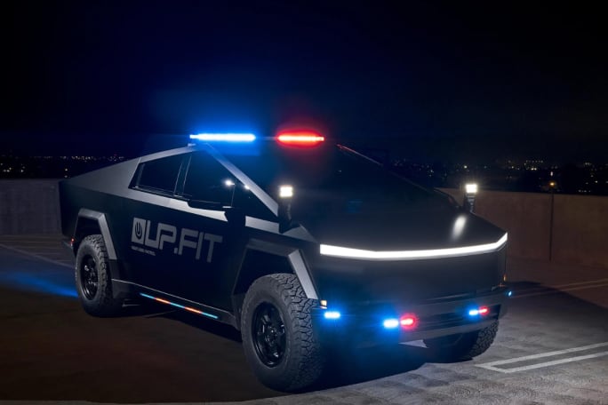 A Tesla Cybertruck is shown, upfitted with police equipment. Red and blue lights, as well as a spotlight, are engaged.