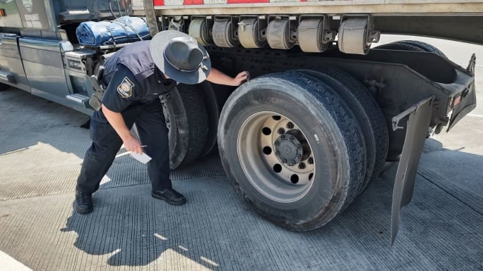 Trooper checking truck tire tread depth
