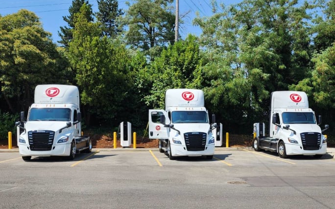 Three Titan Freight Systems eCascadia electric trucks at chargers