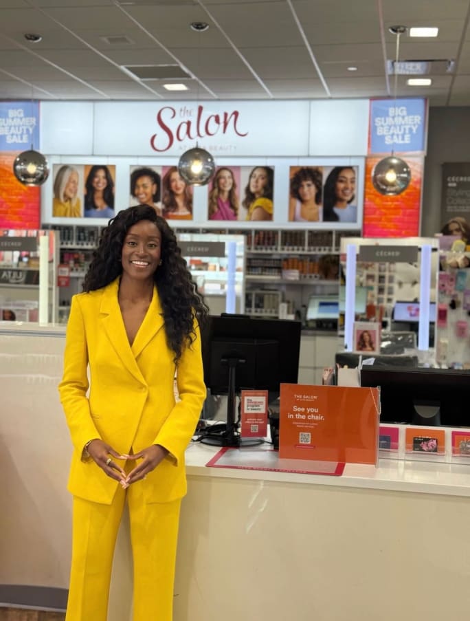 A woman wearing a bright yellow pantsuit stands inside an Ulta store.