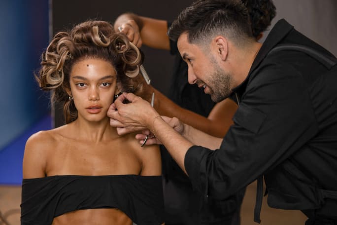 A hairstylist works with a model's curls.