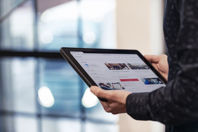 Hands holding a tablet showing Volvo Connect portal.