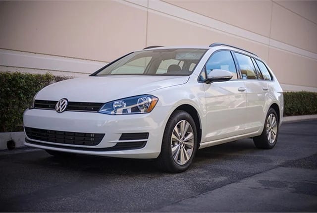 A white 2017 Volkswagen Golf SportWagen 4Motion sits on a road in front of a building.