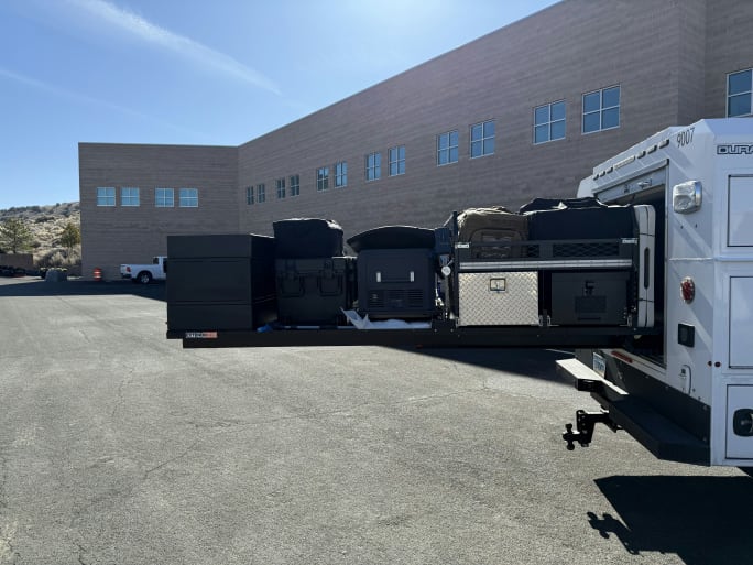 White emergency response vehicles parked beside gray building on asphalt lot