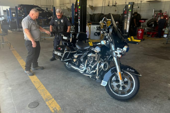 A technician speaks to a Wichita police officer pointing to a motor unit.