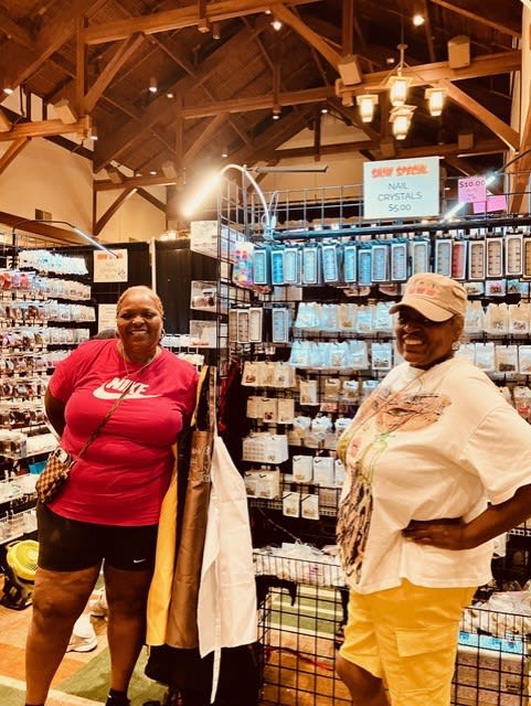 Uniquely Created Bling owner Apryll Cook standing with Sister Simone, both smiling at the event.