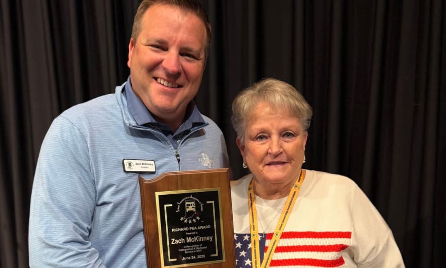 An award winner poses with an award and another STAI member.