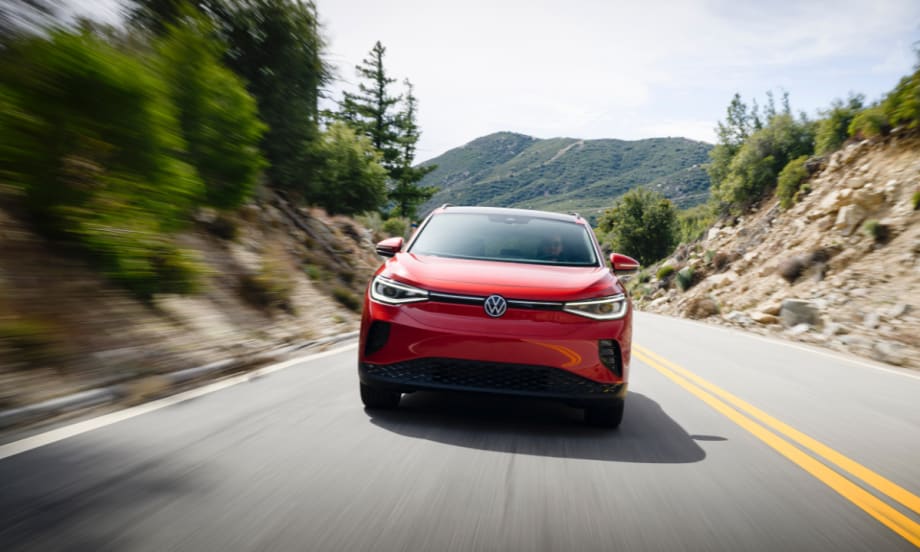 A red Volkswagen ID.4 is seen driving down a winding, mountainous road.
