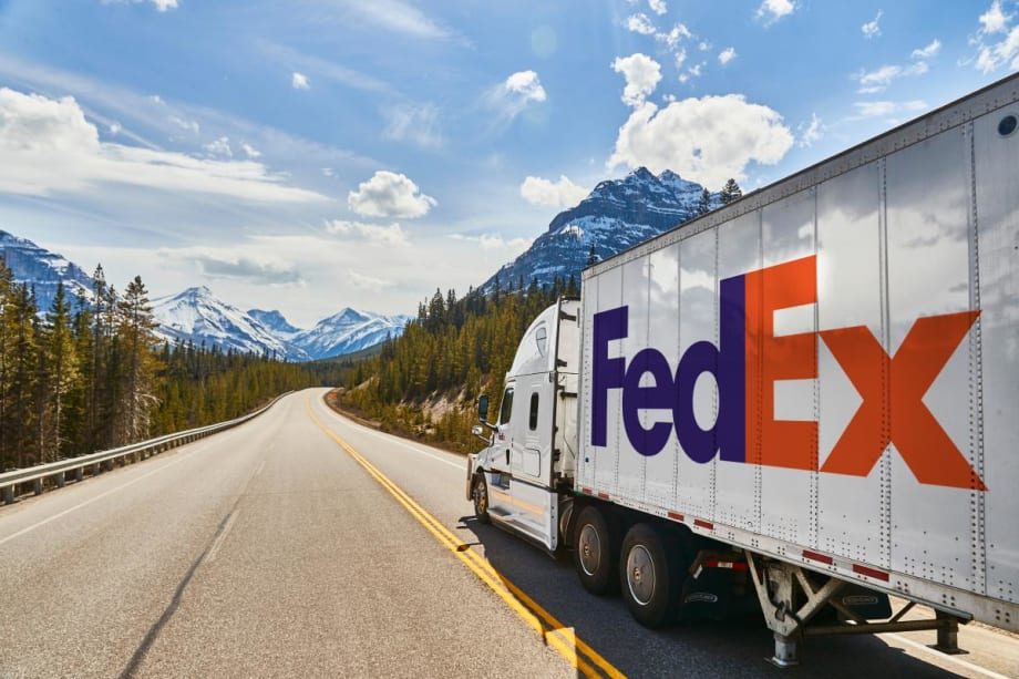 FedEx tractor-trailer on highway with mountains in background