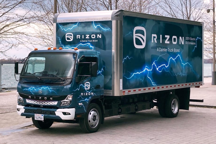 Blue box truck with Rizon on the side of the box parked by a lake.