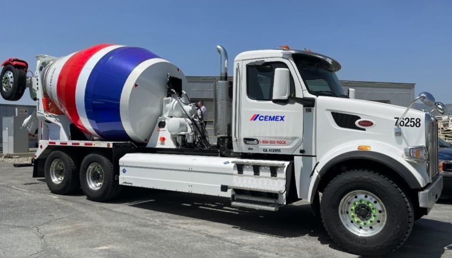 White cement truck with a red strip and a blue stipe.