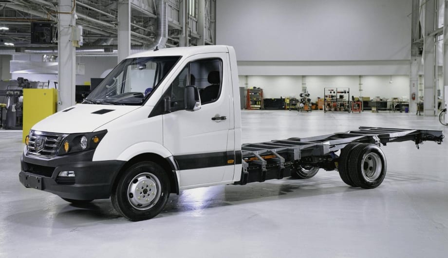 White chassis cab truck is parked inside a building facing left.