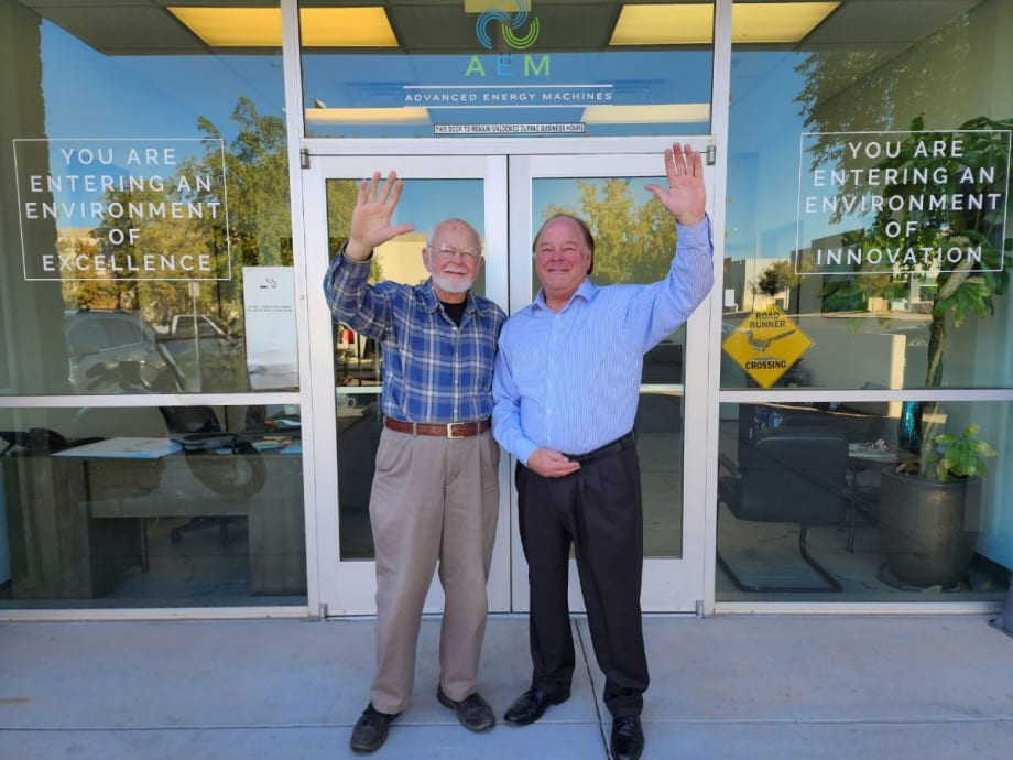 Robert and Ron Koelsch wave in front of the AEM headquarters building.