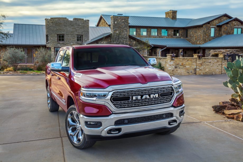 Red Ram 1500 pickup parked in front of a large house.