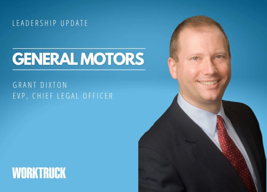 A man in a suit and tie smiling, with the words "General Motors" in the background.