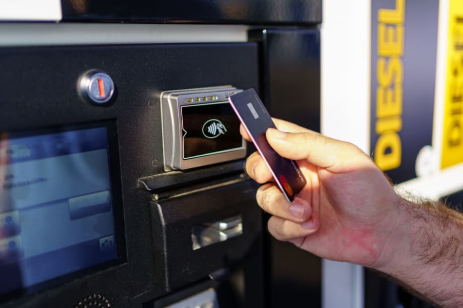 Close up of hand holding a fuel card at the payment portion of a fuel pump.