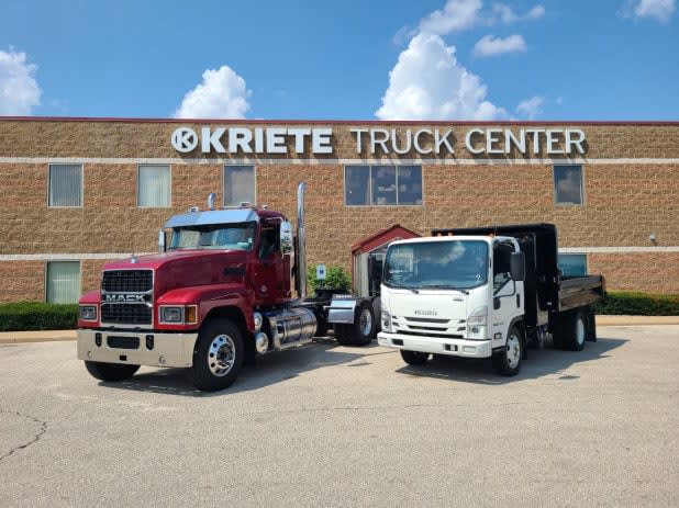 Two trucks parked in front of an industrial building.