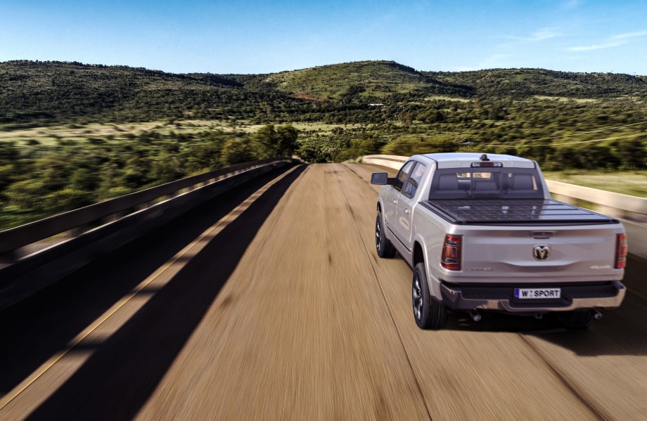 A road with a Ram 1500 equipped with a tonneau cover.