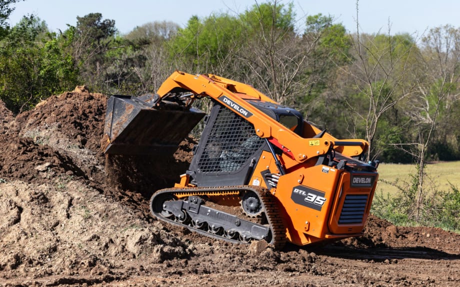 Image of a compact orange digging machine excavating the ground.