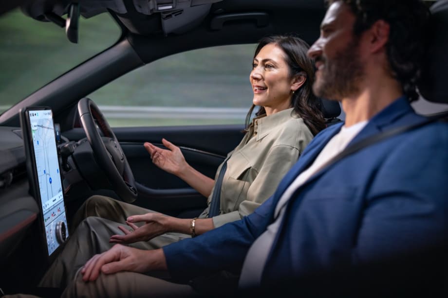 Two people talking in a car, while one drives hands-free.