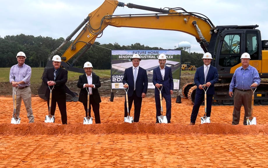 Business and city leaders pose with shovels at groundbreaking event.