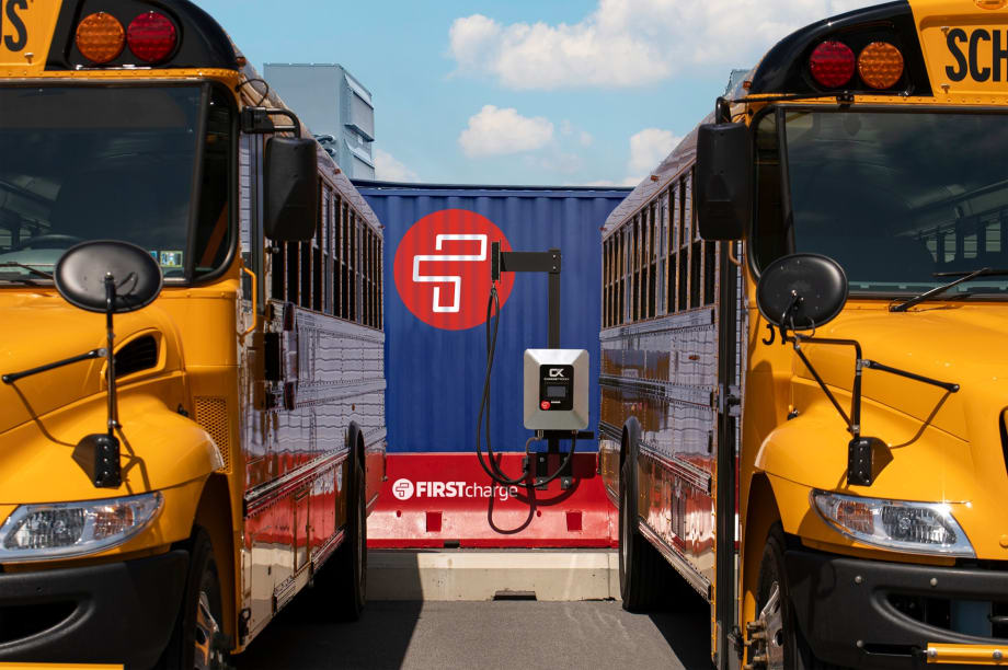 two school buses plugged into a charging station