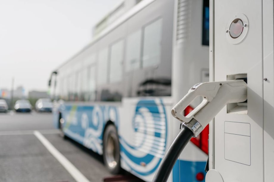 A bus parked at an electric vehicle charging station.